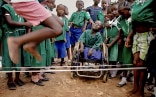 Un gruppo di studenti nigeriani gioca con la corda. Tra loro un bambino con disabilità è su una sedia a rotelle e sorride.