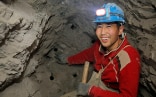 Ein Bergarbeiter mit rotem Pullover und Stirnlampe sitzt in einer Mine. 