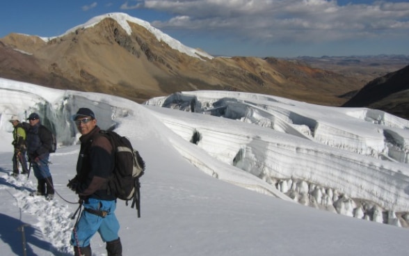 Tres expertos peruanos caminan, encordados, por un glaciar.