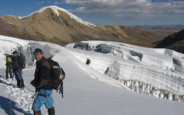 Three Peruvian experts roped together walking on a glacier.