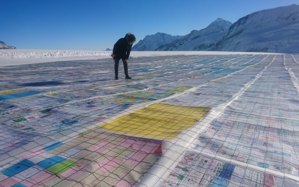 Eine Frau steht auf einem Gletscher und betrachtet einzelne Postkarten