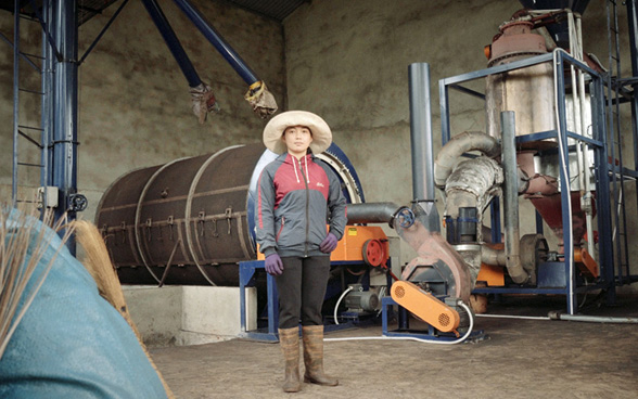 Vietnamese woman standing in front of a pyrolysis coffee dryer.