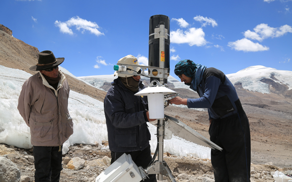 Three men install an automatic weather station in the Peruvian highlands.