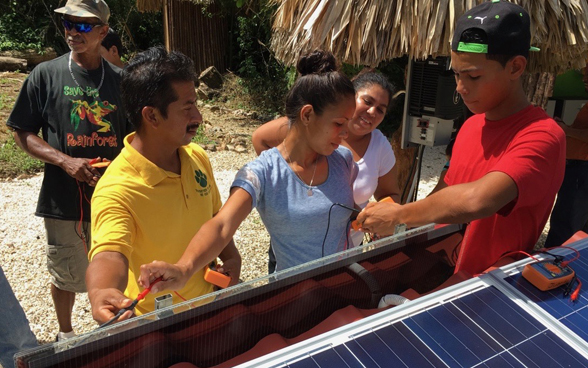Empleados de ZENNA enseñan a un grupo de personas en Belice a utilizar la energía solar.