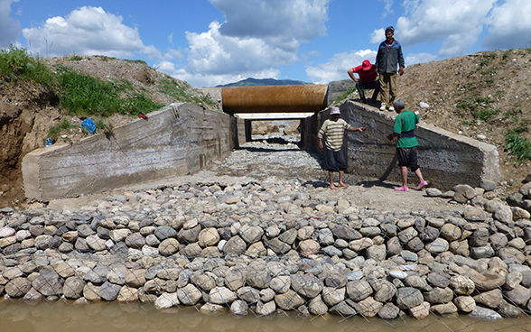 Des hommes se tiennent à côté de la sortie d'un canal d'évacuation des eaux, récemment rénovée.