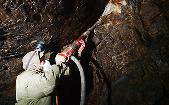 Auf der Suche nach Gold bohrt ein Bergarbeiter ein Loch in den Felsen.