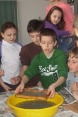 Jungen und Mädchen schauen einem Mitschüler zu, der ein Wasserexperiment vorführt.