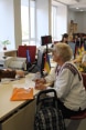Su una fila di postazioni di lavoro, impiegati parlano con varie persone.