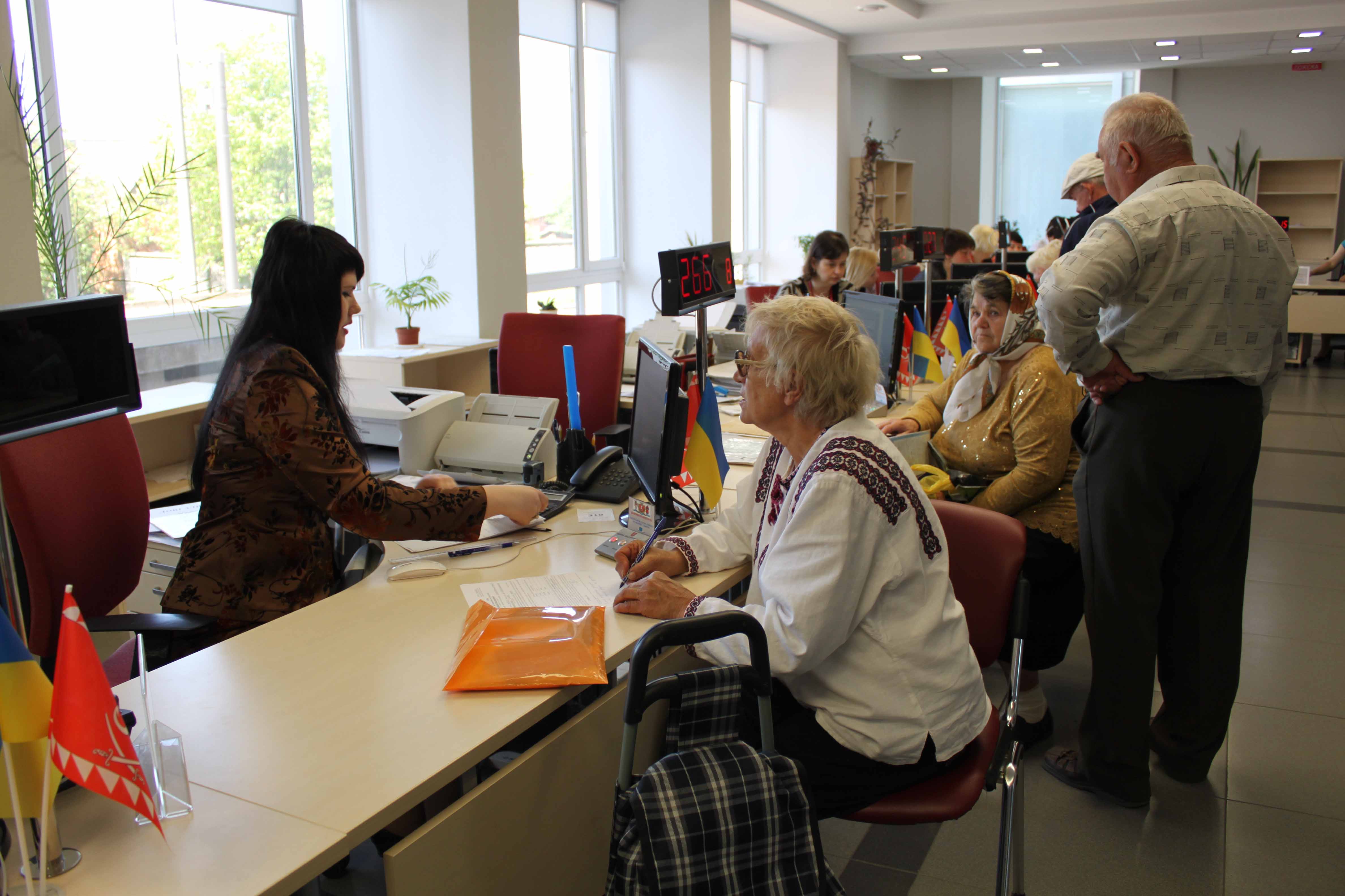 An einer Reihe von Arbeitsplätzen sitzen Angestellte, die jeweils mit verschiedenen Personen sprechen.   