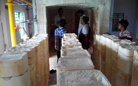 People standing in front of a kiln – an oven to produce ceramics. 