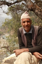 Iswari Prasad Dulal assis à côté du pont.