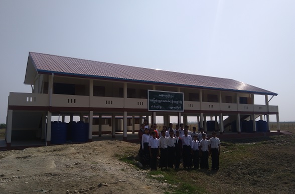 Eine Schulklasse steht vor einer wiederaufgebauten Schule.  