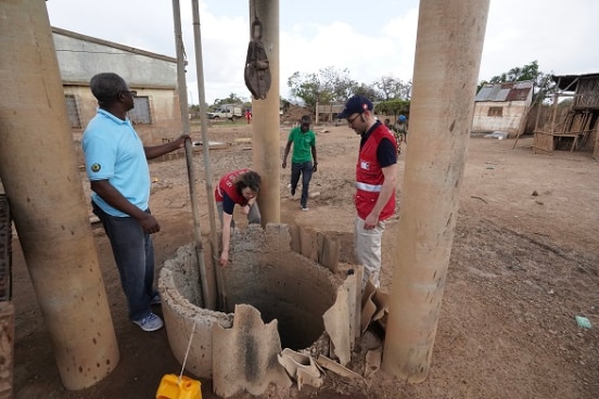 two SHA specialists and their local partners inspects a well