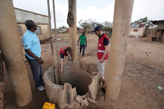 two SHA specialists and their local partners inspects a well