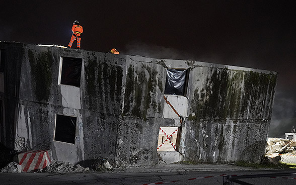 Soccorritori svizzeri appostati su un edificio in rovina durante un’esercitazione notturna.
