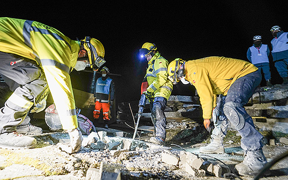 Three members of the team @Fire Germany work on a damaged building in front of three assessors. 