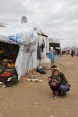 Ein Mädchen und sein Vater neben einem UNHCR-Zelt mit Früchten und Gemüse.