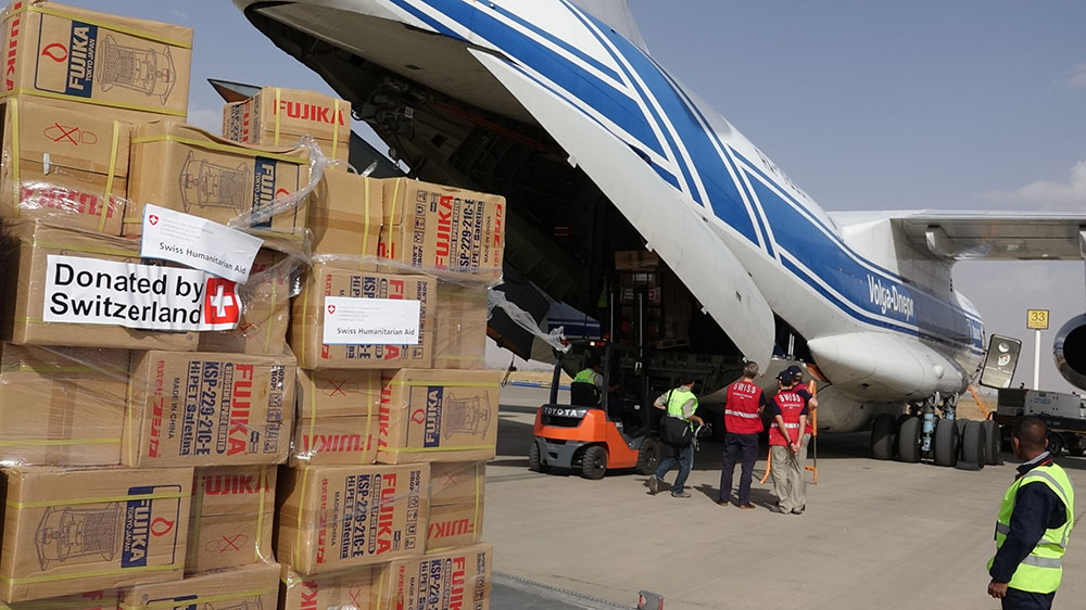 Boxes of Swiss humanitarian aid being unloaded from a cargo plane. 