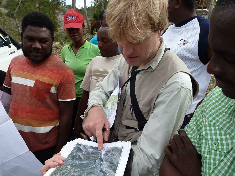 A Swiss specialist standing with a group of Haitian experts pointing at a map.  