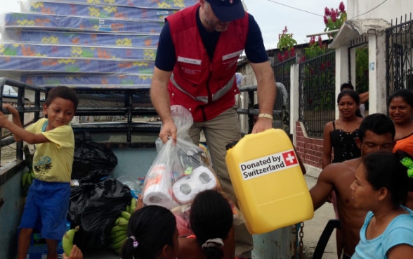 Tre membri del Corpo svizzero d’aiuto umanitario e un collaboratore della Croce rossa ecuadoriana in posa davanti a un rimorchio impiegato per trasportare acqua potabile. 