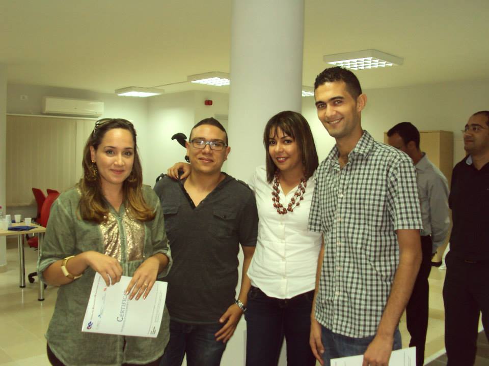 Four young employees at a "practice firm" standing with their work certificates