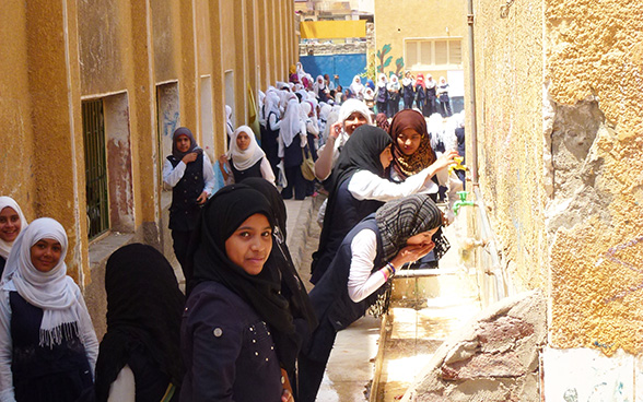 Giovani ragazze di una scuola secondaria di Assuan bevono l'acqua dai rubinetti installati nel cortile di ricreazione.