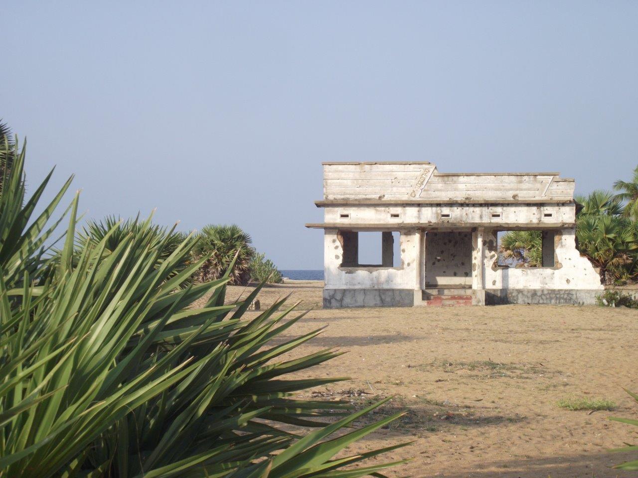 Vue d’une maison située au bord de l’océan et endommagée par des impacts de balle.