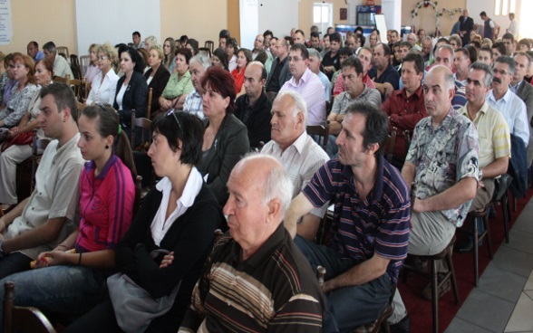 Women and men assembled in a community hall.