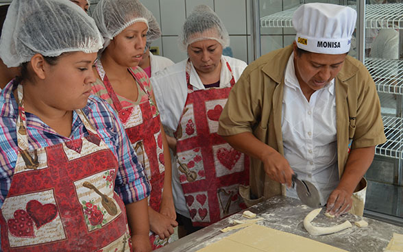 Unas aprendices en panadería-repostería escuchan las explicaciones de una instructora