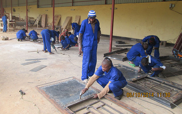 Des apprentis en soudure travaillent sous la supervision d'un instructeur.