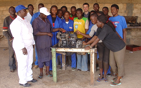 Mujeres y hombres en Burkina Faso alrededor de una mesa con una máquina.