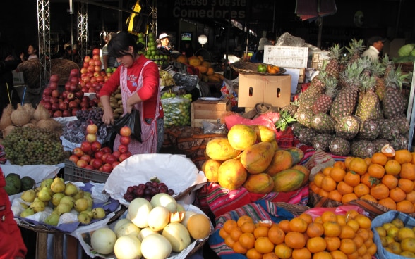 Au milieu des étals de fruits, une femme empile des pommes 