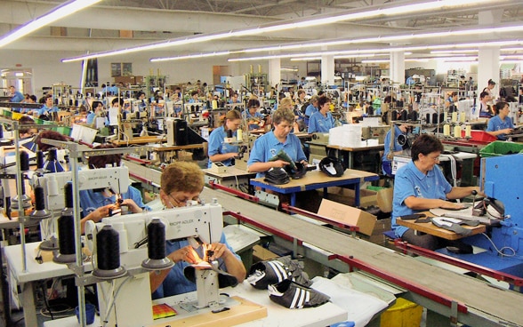 Vue d'un bâtiment d'usine en Bosnie-Herzégovine, où de nombreuses femmes cousent des chaussures sur des machines à coudre.