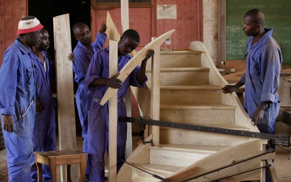  Un groupe de jeunes apprentis menuisiers est en train de monter un escalier.