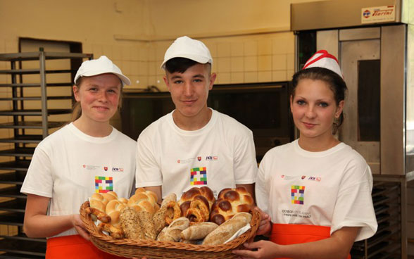 Drei junge Bäckerlehrlinge zeigen selbstgebackenes Brot.