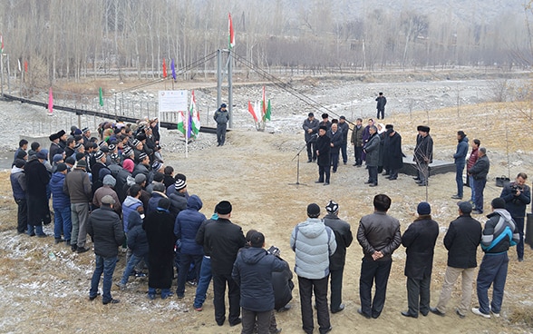 Une trentaine de personnes sont rassemblées autour d’un homme faisant un discours pour l’inauguration d’un canal d’irrigation