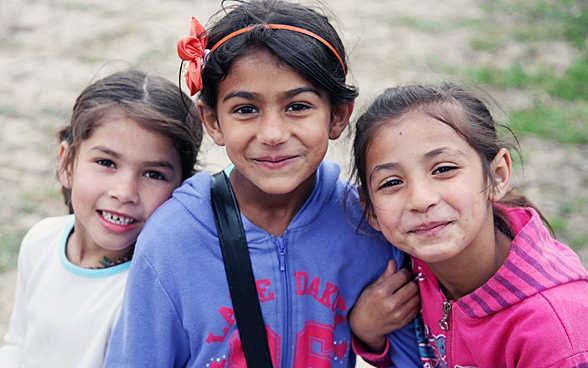  Three Roma girls smile at the camera.