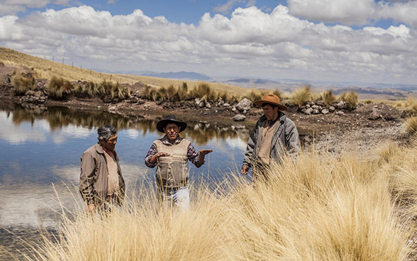 Tre uomini discutono davanti a una riserva idrica.