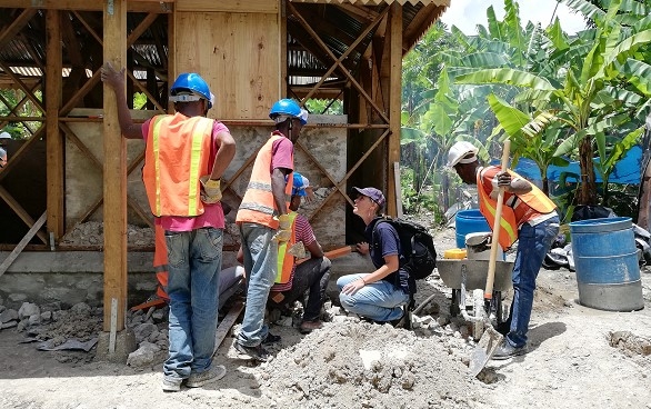 A female specialist from the Swiss Humanitarian Aid Unit in front of a construction site with Haitian specialists. 