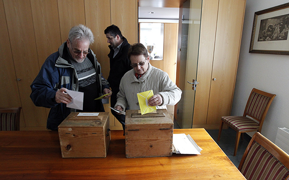 Un couple dépose ses bulletins de vote dans les urnes.