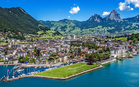 Vue de la ville de Brunnen d'en haut avec la place des Suisses de l'étranger bien visible, le lac et les montagnes en arrière-plan.