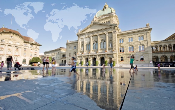 Bundesplatz and the Federal Palace with a world map projected against the sky. (Symbolbild)