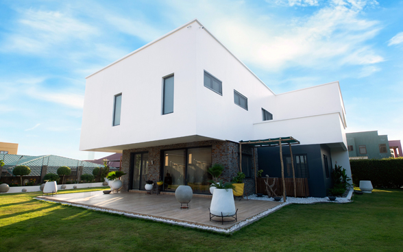 A white, modern-looking house with a terrace and garden.