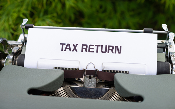 La mention Tax Return est inscrite sur une feuille de papier introduite dans une machine à écrire. 