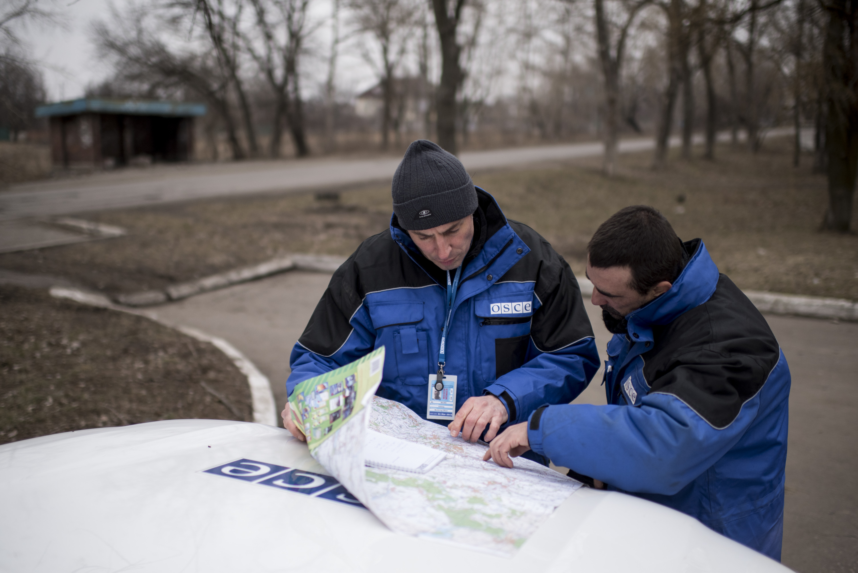 Des moniteurs de l’OSCE lisent une carte sur le capot d’une voiture