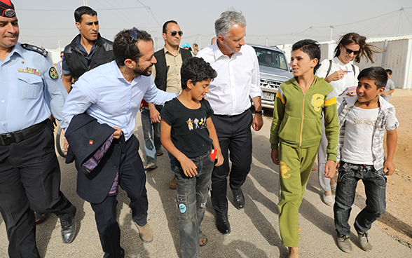 Didier Burkhalter walking through the Azraq camp accompanied by officials and young refugees