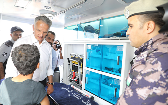 Der Bundesrat spricht mit einem Knaben in einem Rettungswagen, den die Schweiz Jordanien schenkte.