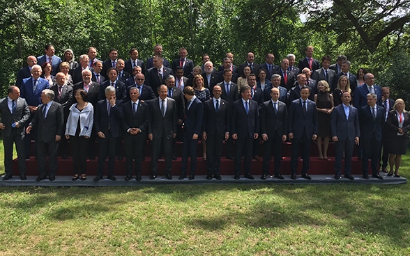 Les ministres des affaires étrangères participant à la rencontre de l’OSCE se tiennent sur la pelouse pour une photo de groupe