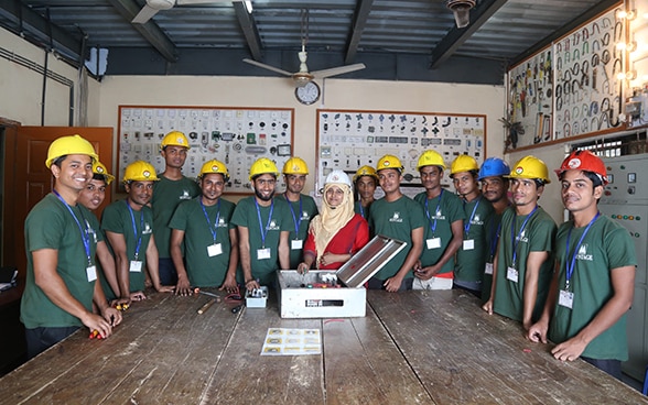 Un gruppo di uomini e una donna si ergono attorno a un tavolo di legno.