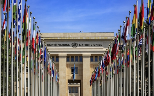 L’edificio del Palazzo delle Nazioni Unite a Ginevra e il viale con le bandiere spiccano nella notte.